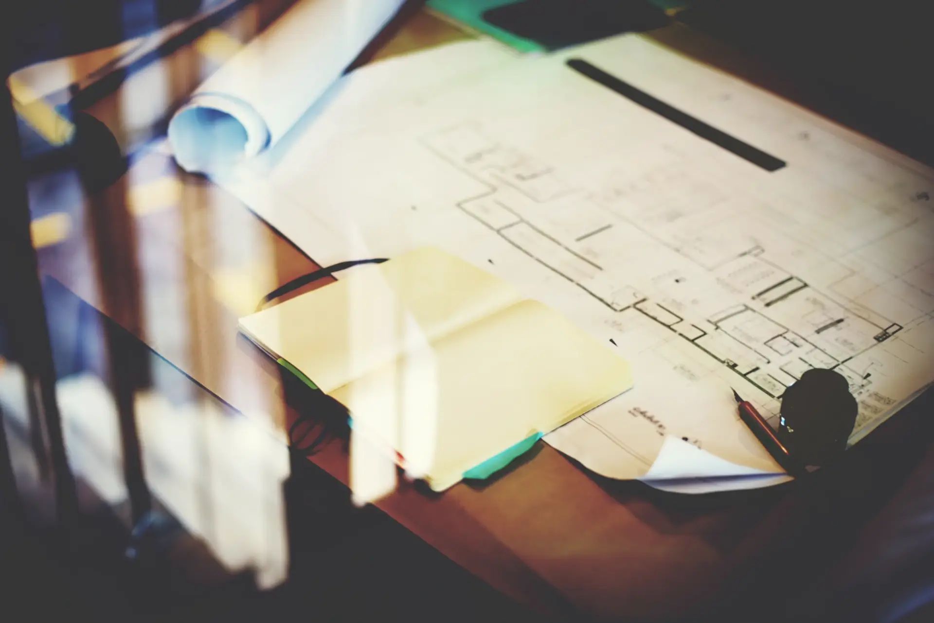 Architectural blueprints and a notebook on a desk, essential for Custom Home Building in South Carolina.
