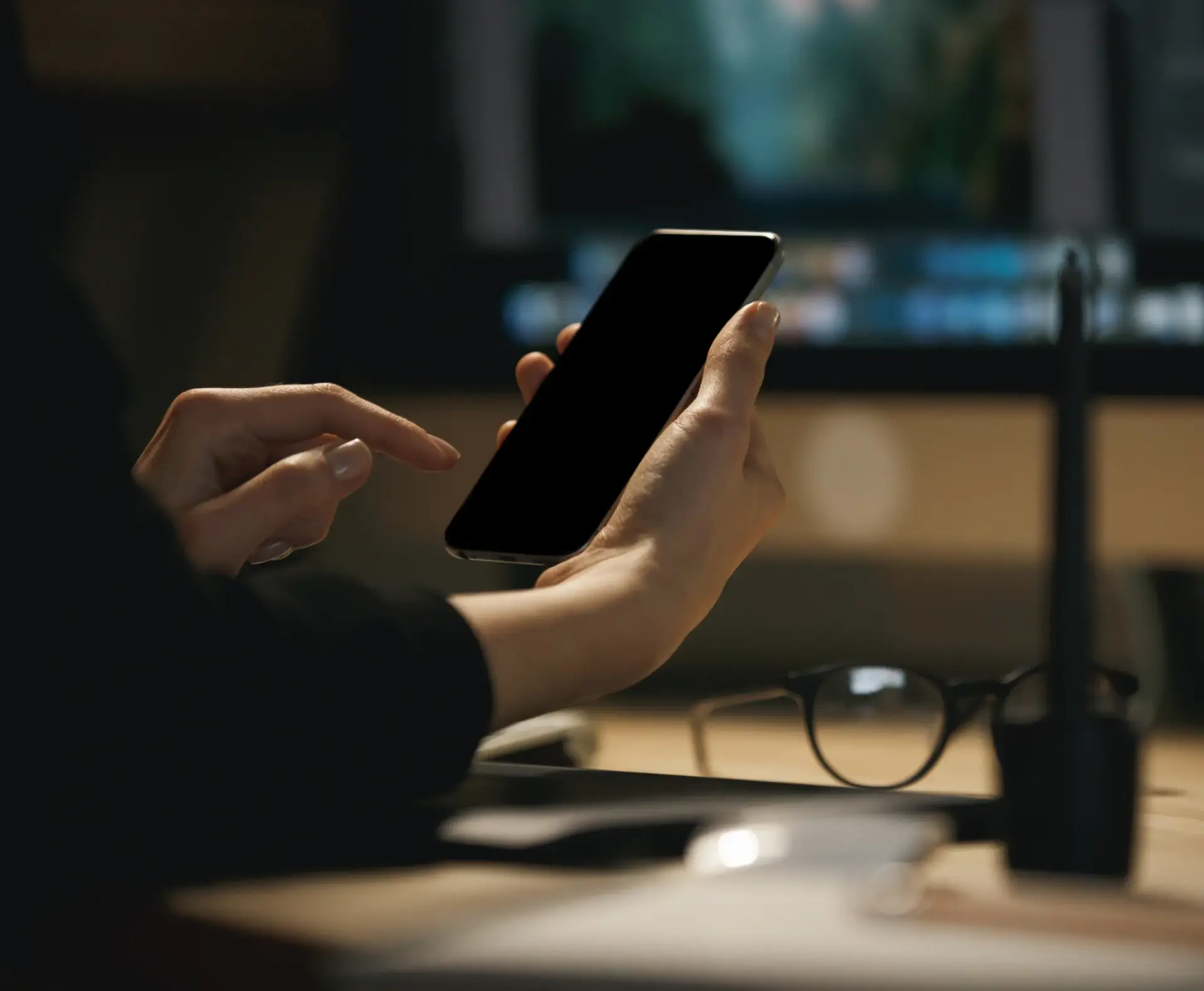 Person using a smartphone at a desk to contact Custom Home Builders in South Carolina regarding a new project.