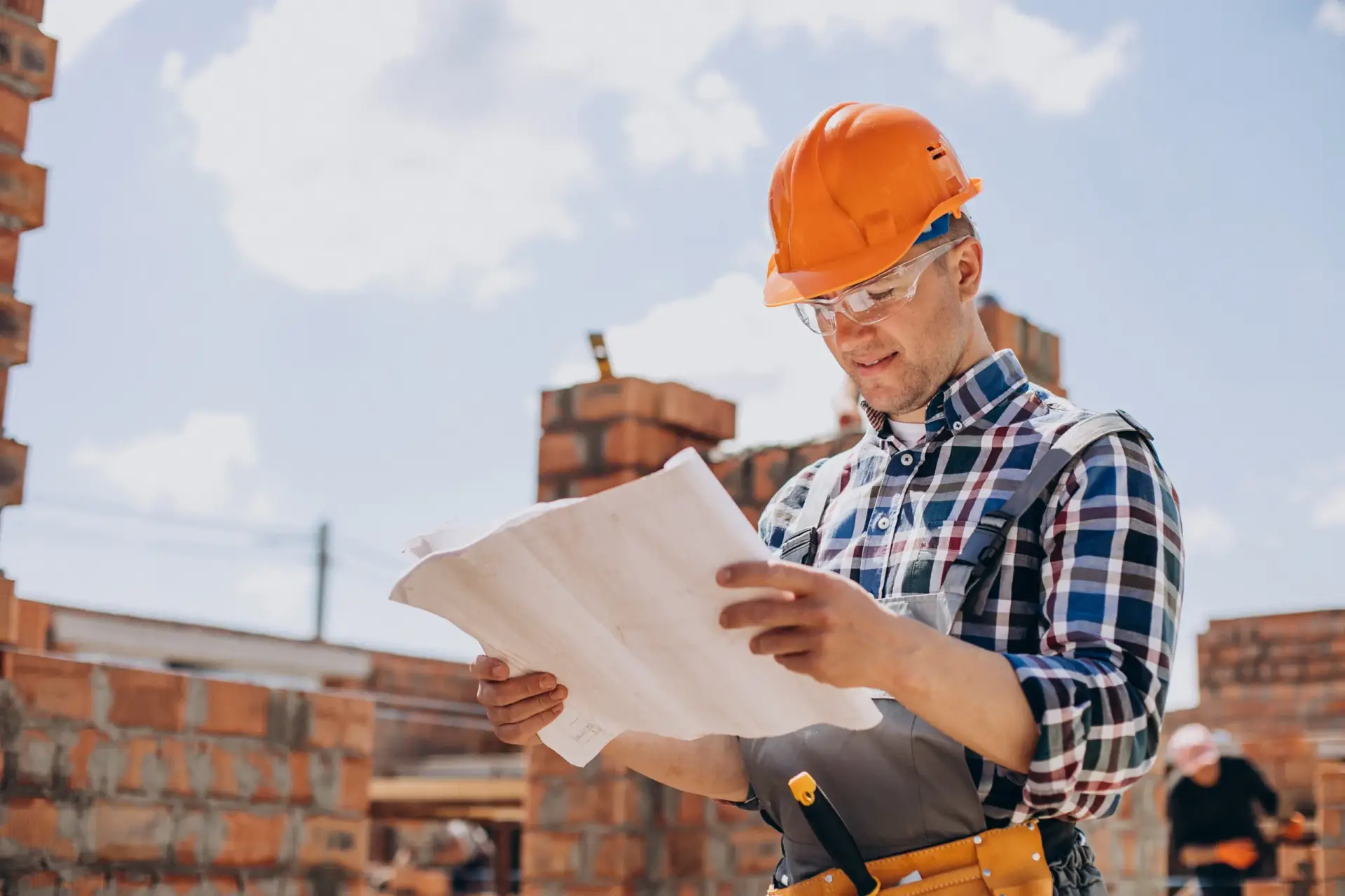 A builder in a hard hat reviewing blueprints at a site for Custom Home Building in South Carolina.