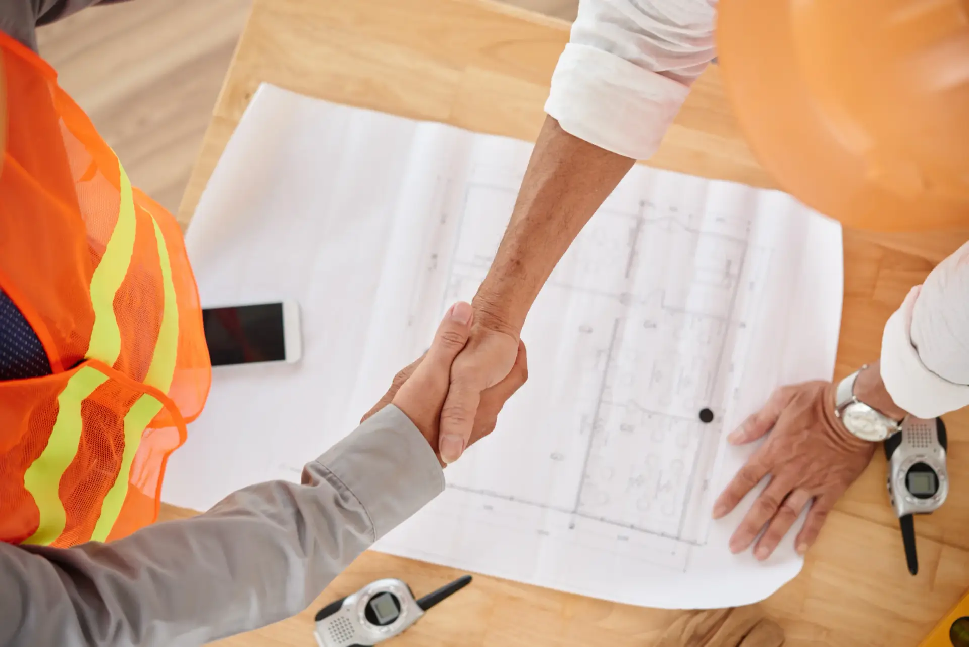 Handshake between two engineers over house blueprints, symbolizing reliable Construction Consulting in South Carolina.